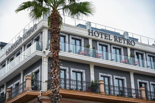 a hotel with a palm tree in front of a building at Hotel Retro in Batumi