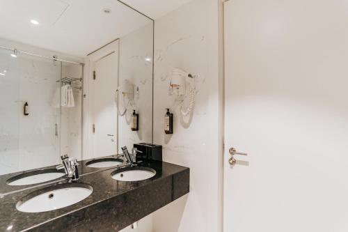 un bagno con due lavandini e una doccia di Hotel Premium Porto Downtown a Porto