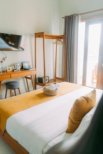 a bedroom with a bed with a desk and a window at Escape Bajo in Labuan Bajo