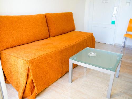 a orange couch and a table in a room at Aparthotel Villas La Manga in La Manga del Mar Menor