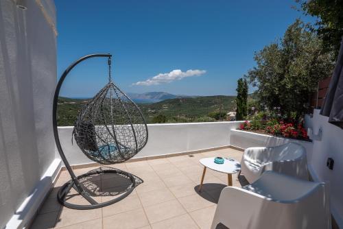 a patio with a swing and a chair on a balcony at The Little White House in Koukounará