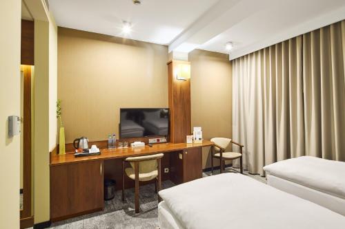 a hotel room with a desk with a tv and a bed at Hotel Na Półboru in Sieradz