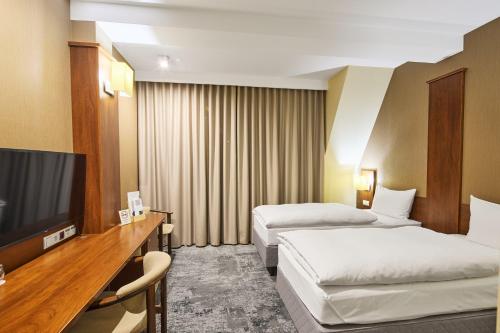 a hotel room with two beds and a flat screen tv at Hotel Na Półboru in Sieradz