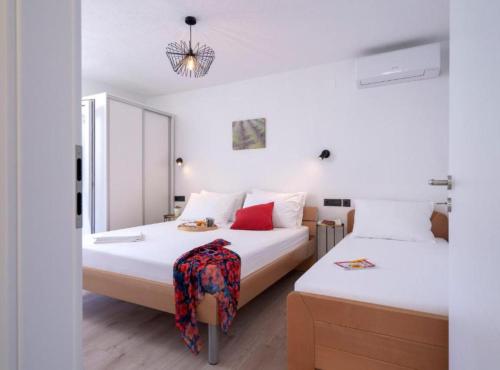 1 Schlafzimmer mit 2 Betten mit weißer Bettwäsche und roten Kissen in der Unterkunft Vacation House Jadranko in Gdinj