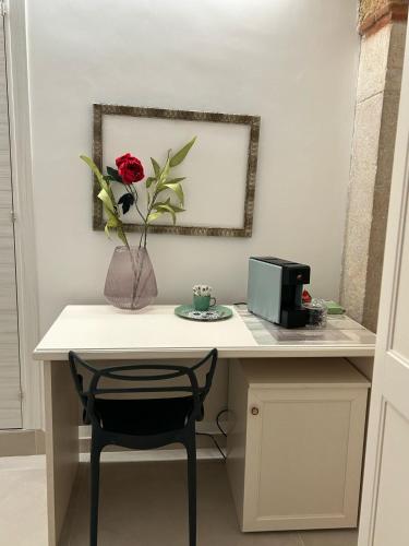 a desk with a flower in a vase on it at B&b Bianco Rooms in Orta Nova