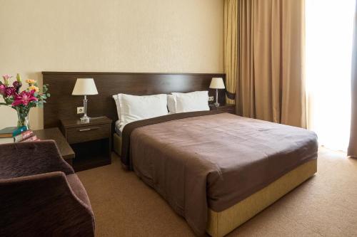 a hotel room with a large bed and a window at Kainar Hotel in Shymkent