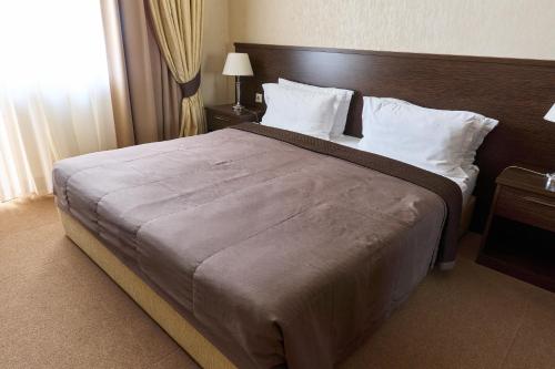 a bedroom with a large bed with a wooden headboard at Kainar Hotel in Shymkent
