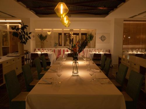 a long table in a restaurant with white tables and chairs at Hostal Empúries in L'Escala