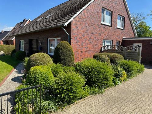 una casa de ladrillo con arbustos delante de ella en Ferienhaus Janßen, en Esens