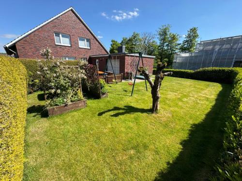 un jardín con un árbol en medio de un patio en Ferienhaus Janßen, en Esens