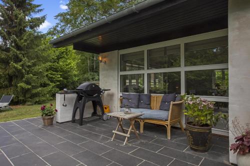 a patio with a grill and a couch and a table at Holiday Home With A Wilderness Bath, Only 100 Meters From The Lovely Beach in Marielyst