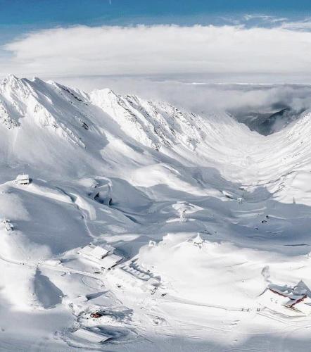 a mountain covered in snow with clouds in the background at Hotel of Ice Transylvania in Cîrţişoara