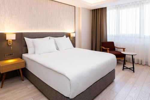 a bedroom with a large white bed and a chair at The Emporia Hotel in Pamukkale