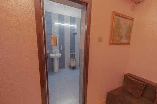 a bathroom with a toilet and a glass door at UDUPI HOMESTAY Garden Villa in Udupi