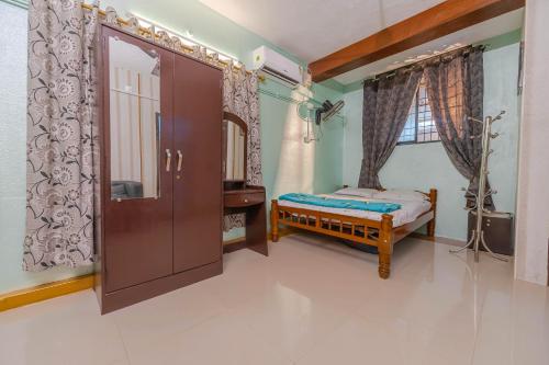 a bedroom with a small bed and a mirror at UDUPI HOMESTAY Garden Villa in Udupi