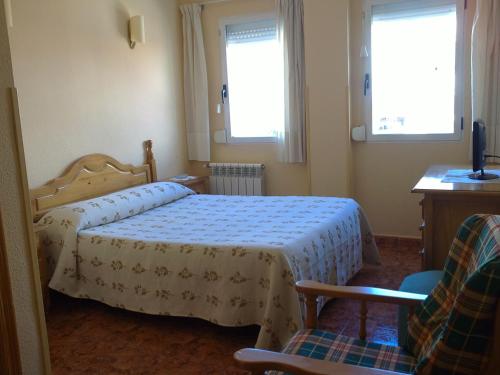 ラ・ヌシアにあるHostal Sunamiのベッドルーム1室(ベッド1台、椅子2脚、窓2つ付)