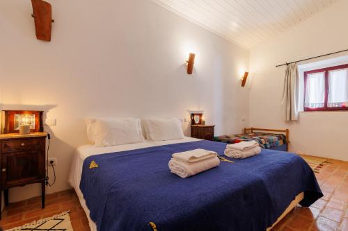 a bedroom with a blue bed with towels on it at Monte do Pantaleão in Baleizão