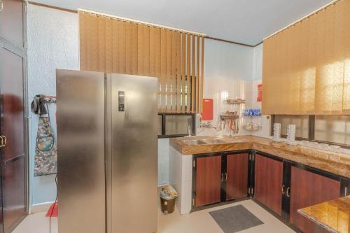 a kitchen with a stainless steel refrigerator and wooden cabinets at UDUPI HOMESTAY Garden Villa in Udupi