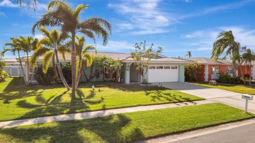 a house with palm trees and a driveway at The Crown House 4b Pool Home 6 mins to IR Beach in Largo
