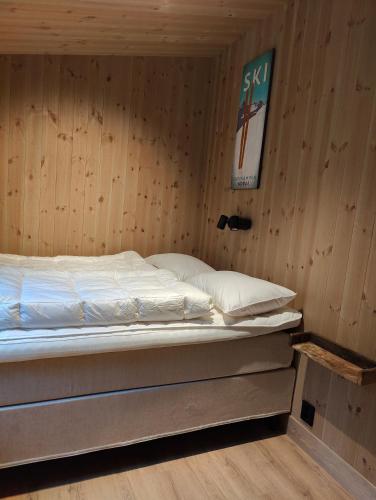 a bed in a room with a wooden wall at Nye leiligheter på Blomberg i Hafjell in Hafjell
