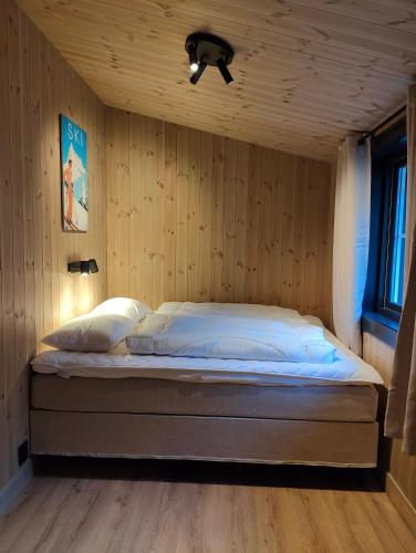 a bedroom with a bed in a wooden wall at Nye leiligheter på Blomberg i Hafjell in Hafjell