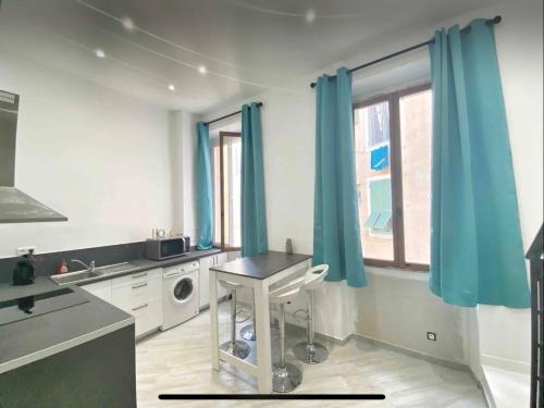 une cuisine avec des rideaux bleus, une table et une fenêtre dans l'établissement Welcome ! Entre colline du Château et le port, à Nice