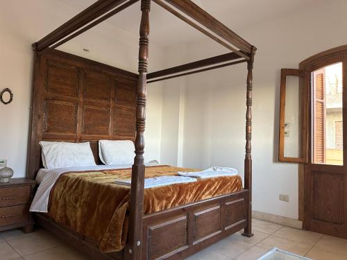 a canopy bed with a wooden frame in a bedroom at Sunset Haven in Luxor