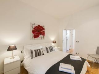 a white bedroom with a large white bed with a table at Casa Rinuccini in Florence