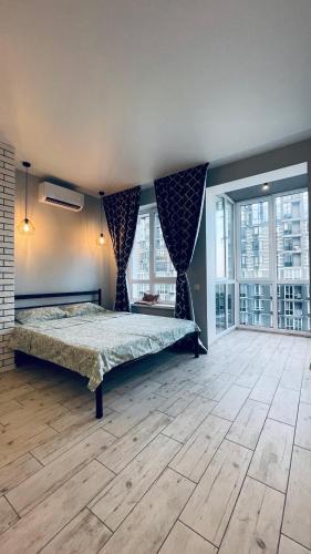 a bedroom with a bed in a room with windows at Апартаменти студія в Гранд Бурже in Bucha