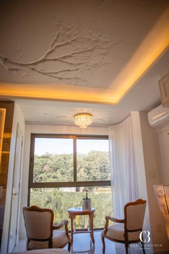 a room with a large window and a table and chairs at Casa Valduga Pousada Boutique in Bento Gonçalves