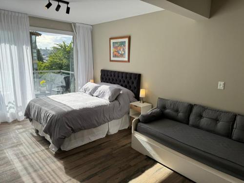 une chambre avec un lit, un canapé et une fenêtre dans l'établissement Departamento Güemes, à San Carlos de Bariloche