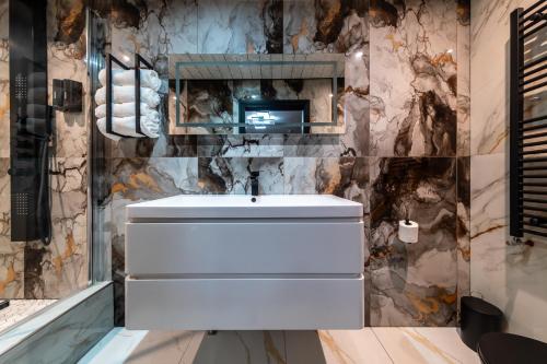 a bathroom with a white sink and a marble wall at MyNites in Birmingham