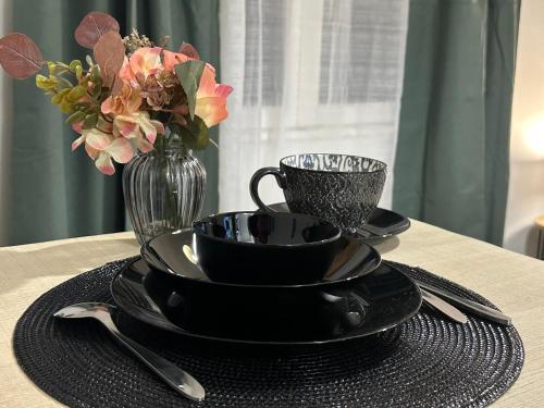 une table avec des assiettes noires et un vase avec des fleurs dans l'établissement Studio meublé wifi ELM, à Tonneins