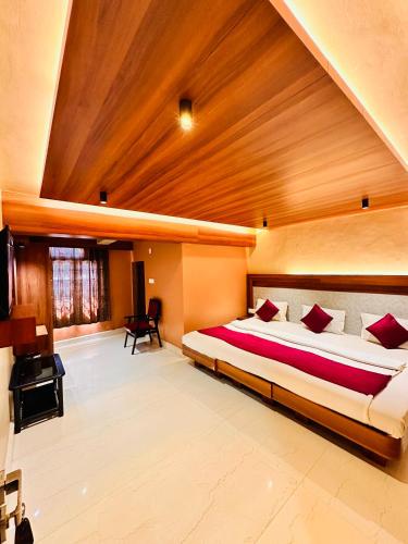 a bedroom with a large bed and a wooden ceiling at City Palace Hotel in Ooty