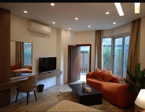 a living room with a orange couch and a television at Maison 7 New Cairo in Cairo