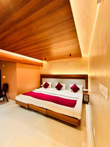 a bedroom with a large bed with red pillows at City Palace Hotel in Ooty