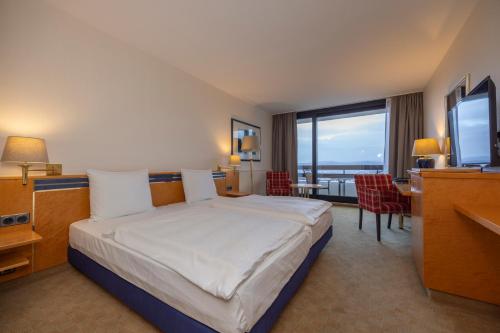 a hotel room with a bed and a desk and a television at Fletcher Hotel-Restaurant Arnsberg-Sauerland in Arnsberg