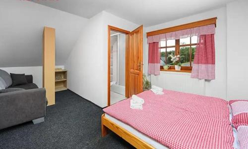 a bedroom with a pink bed and a couch at Penzion pod Ještědem in Hoření Paseky