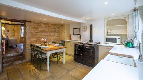 a kitchen with a table and a stove top oven at Mouse Manor in Longborough