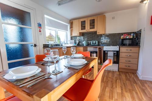 a kitchen with a wooden table with wine glasses at Beach House in Thurso