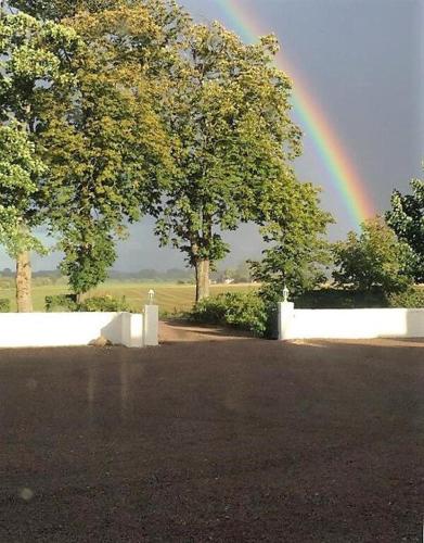 a rainbow over a white fence and trees at Amazing Home In Höganäs With 2 Bedrooms And Wifi in Höganäs
