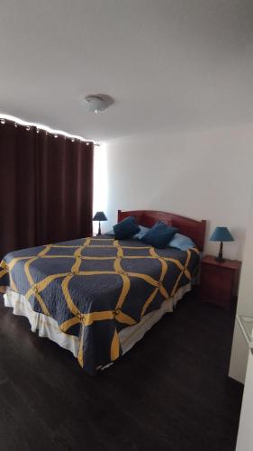 ein Schlafzimmer mit einem Bett mit einer blauen und gelben Bettdecke in der Unterkunft Mirador 2 de Playa Brava in Iquique