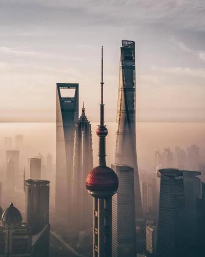 a group of tall buildings in a foggy city at Dayin Youth Hostel - East Nanjing Road & People's Square & The Bund -Large Social Area -Bar -Café -Gym -Free Laundry Luggage Storage -24H Front Desk -English Service in Shanghai
