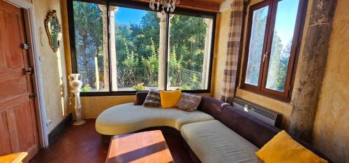 un salon avec un canapé et quelques fenêtres dans l'établissement Maison au cœur des Cévennes, à Molières-Cavaillac