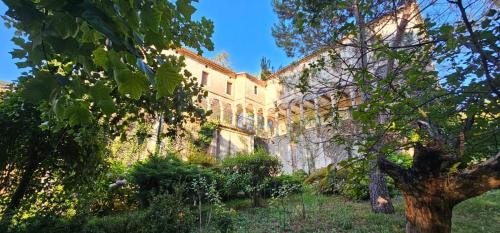 un vieux bâtiment avec des arbres devant lui dans l'établissement Maison au cœur des Cévennes, à Molières-Cavaillac