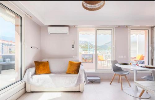 - un salon avec un canapé, une table et des fenêtres dans l'établissement 2P - terrasse - parking - plage, à Menton