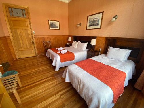 a hotel room with two beds and a clock on the wall at Hotel Plaza in Punta Arenas