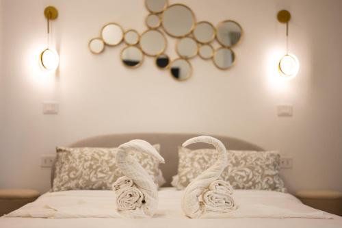 a bed with towel swans on it with two lights at Enjoyhousebracciano Suite 3 in Bracciano