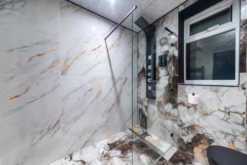 a glass shower in a bathroom with white marble walls at MyNites in Birmingham