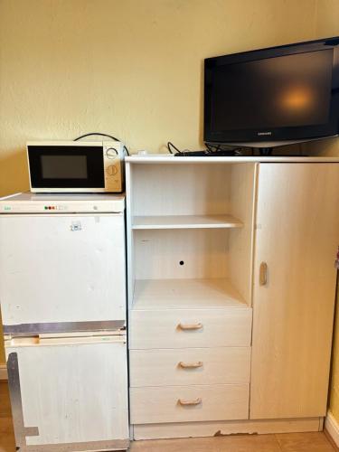 a white cabinet with a microwave and a television on it at Laburnum Guest House in Colnbrook